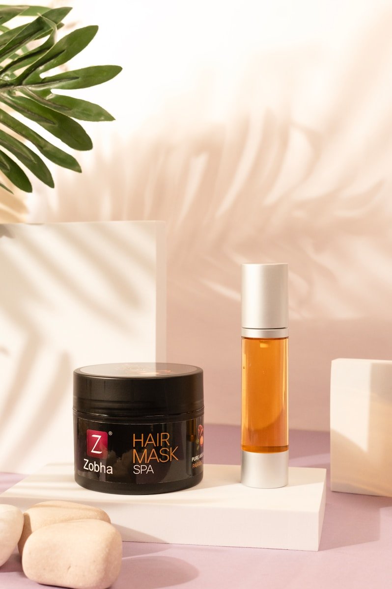 A table topped with a jar of hair mask next to a plant