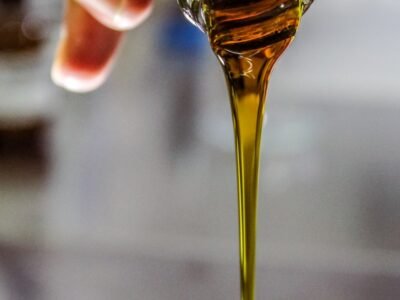 person holding clear drinking glass with brown liquid
